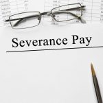 A white paper with the words "Severance Pay" along with a pen and a pair of glasses kept on top of documents of an employee who did not receive a fair severance package.