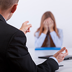 wrongful_dismissal_squareimage A female professional cries over wrongful dismissal charges as her boss aggressively points at her.